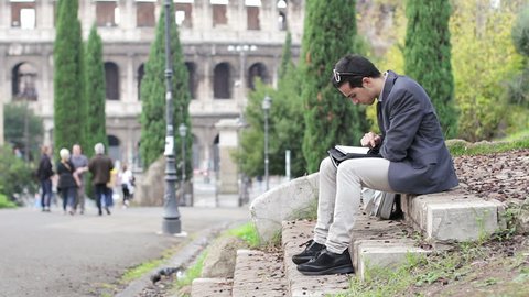 Young business man working in park in Rome, near Colosseum