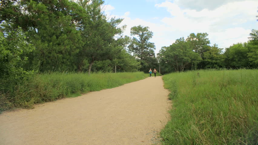 Two young girls are jogging in the park.