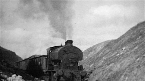 Cranford, Northamptonshire, UK - August, 1964: A grainy old black and white film of a steam railway locomotive engine named Cranford hauling a freight train of mineral wagons in an ironstone quarry.