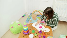 Shot of mother and small baby boy painting pictures in playroom.