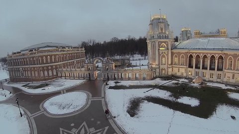 Tourists walk near palace complex with illumination in Tsaritsyno at winter evening in Moscow. Aerial view