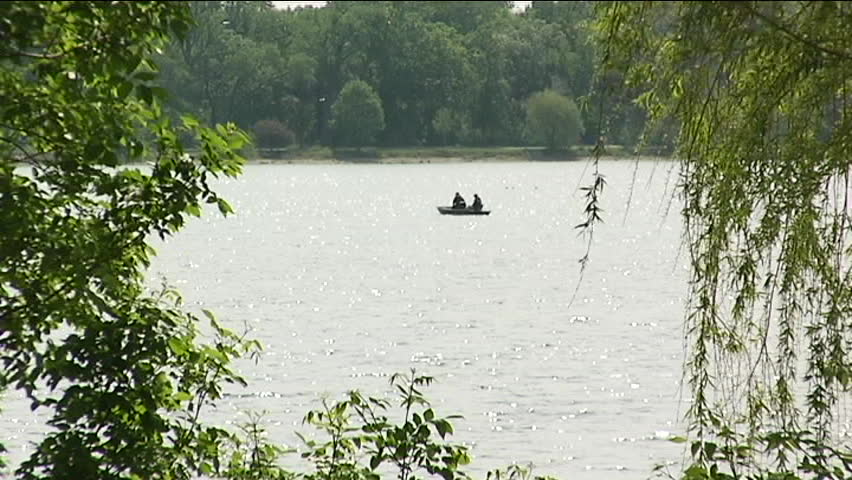A canoe drifts on idyllic Minneapolis Lake Calhoun. In the foreground, joggers pass by, enjoying the summer day.
