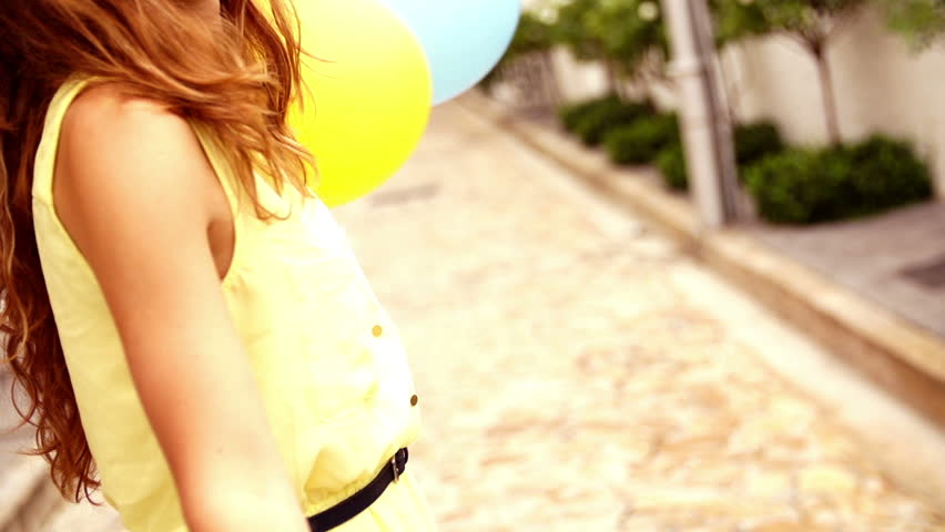 Close up of teenage girl playing with colorful balloons in slow motion