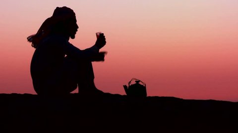 WADI RUM, JORDAN CIRCA 2013 - A Bedouin man pours tea in silhouette against the sunset.