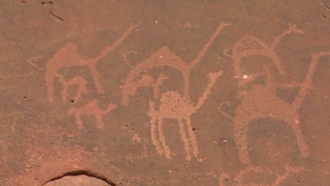WADI RUM, JORDAN CIRCA 2013 - Close up of ancient and mysterious petroglyphs depicting humans and camels in the Saudi desert near Wadi Rum, Jordan.