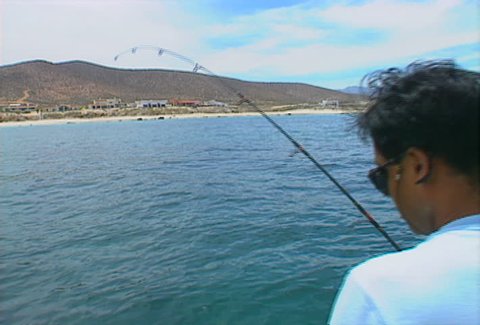 A fisherman reels in an Orangeside Triggerfish, off the coast of Baja California.