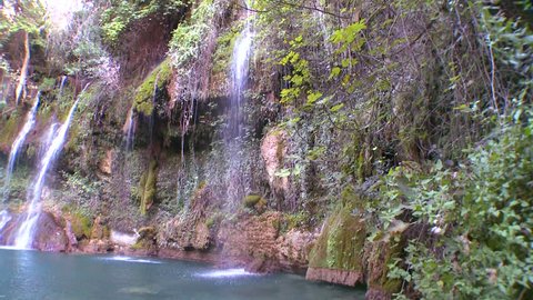 CIRCA 2013 - A tropical waterfall flows into a green pool.