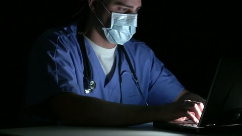 Surgeon working on a laptop in a dark room