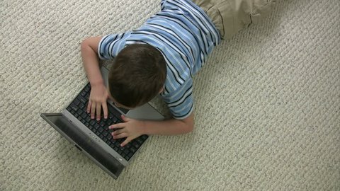 Overhead shot of a kid typing on a computer
