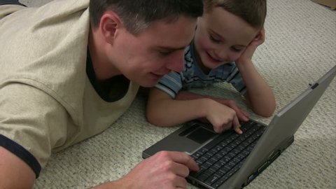 Dad and son working on a laptop computer together
