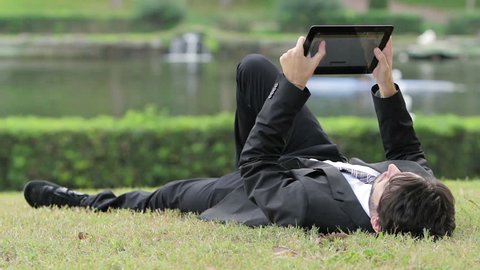 Young Businessman working with tablet computer outdoor in park