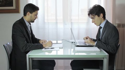 Two business people with tablet and laptop talk about a project