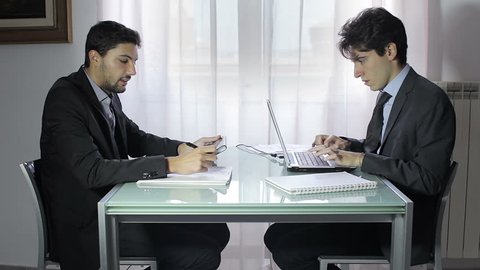 Two business people in elegant suits sitting at desk working in team together