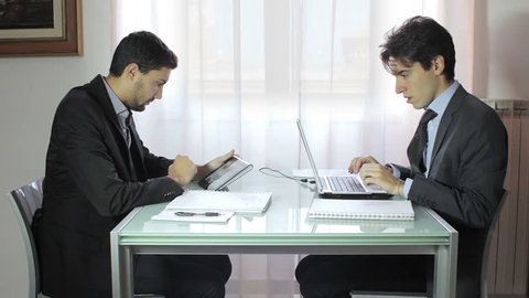 Two young businessmen discussing document in touchpad
