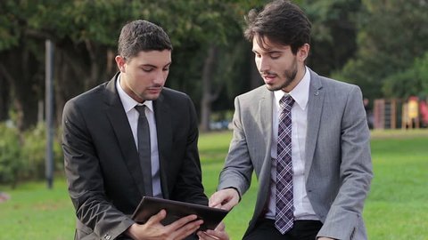 Business meeting in a park with electronic tablet
