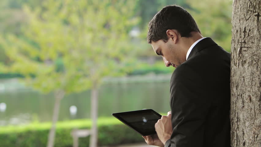 Business man using digital tablet at park