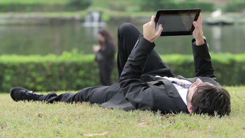 Businessman working outdoors with digital tablet PC at the park.