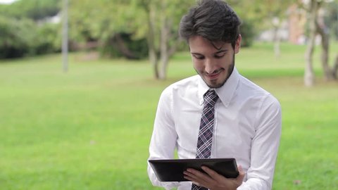Young businessman at the park working with tablet