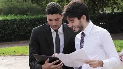 Two happy businessmen working with tablet computer