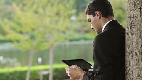 Young Businessman using tablet PC outside on a park