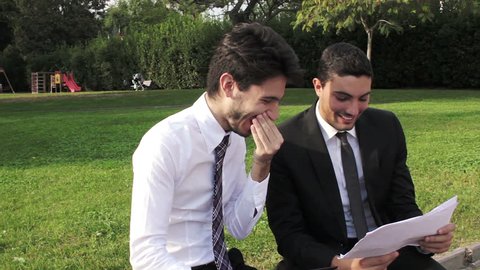 Two business people with tablet computer talk about a project on a park bench