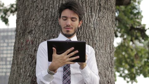 Business man using digital tablet at park