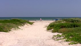 Video zoom in of a flag of Texas on a beach at Padre Island National Park. Path through sand dunes to beach. Family fun near waves. Don Despain of Rekindle Photo.