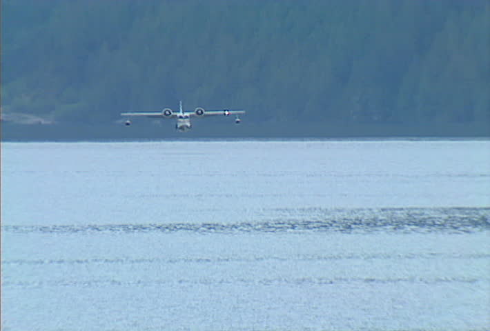 A flying boat lands on the surface of a mountain lake.