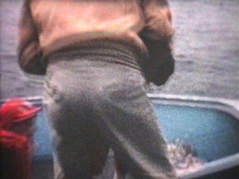 A father puts his two children in an aluminum boat as he gets ready to go for a boat ride on the lake. (Vintage 8mm film)