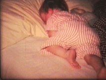 A little girl tosses and turns trying to sleep in her bed. (Vintage 8mm film)