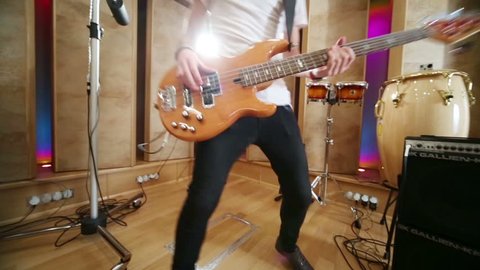 Young man plays guitar and jumps next to drums in recording studio Stockvideó