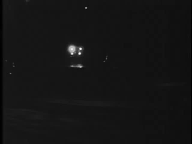 Police car traveling down road at night, 1940s