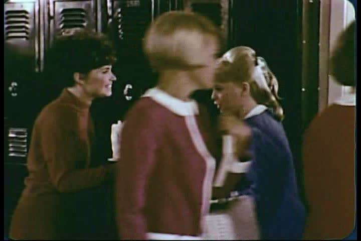 CIRCA 1960s - Two teenage girls plan a party in the hallway of a highschool during the 1960s