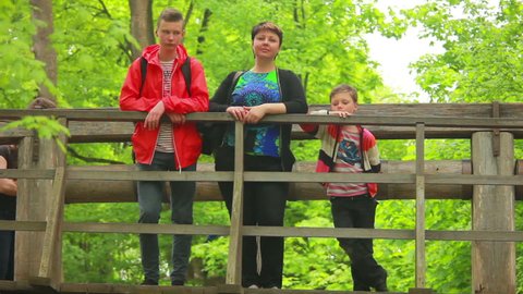 mother with children standing on an old wooden bridge and looking at the camera
