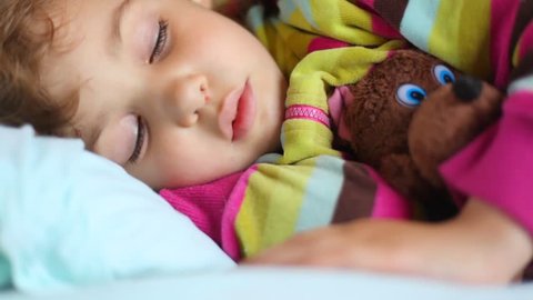little girl sleeping with toy bear in compartment of railway carriage 