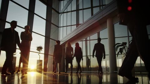 Diverse business group walking through modern office building at sunset