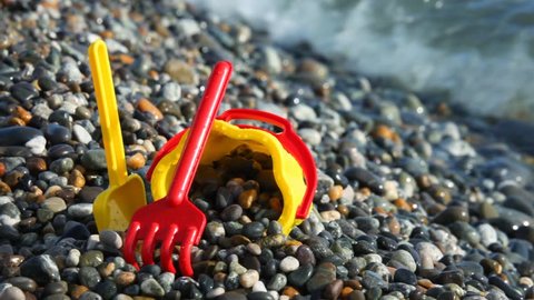 yellow children's bucket with scoop on pebble seacoast 