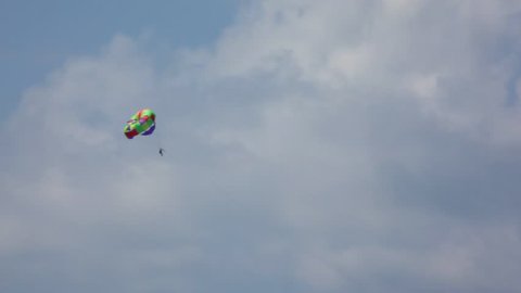 parasailling, man with parachute flying in sky 