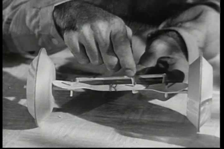 CIRCA 1950s - At a family picnic in 1950 a father uses tableware to build a model of a Chevrolet, showing off such innovations as center point steering, springs and shackles, shock absorbers