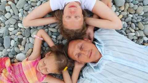 happy family lying on pebble beach, top view 