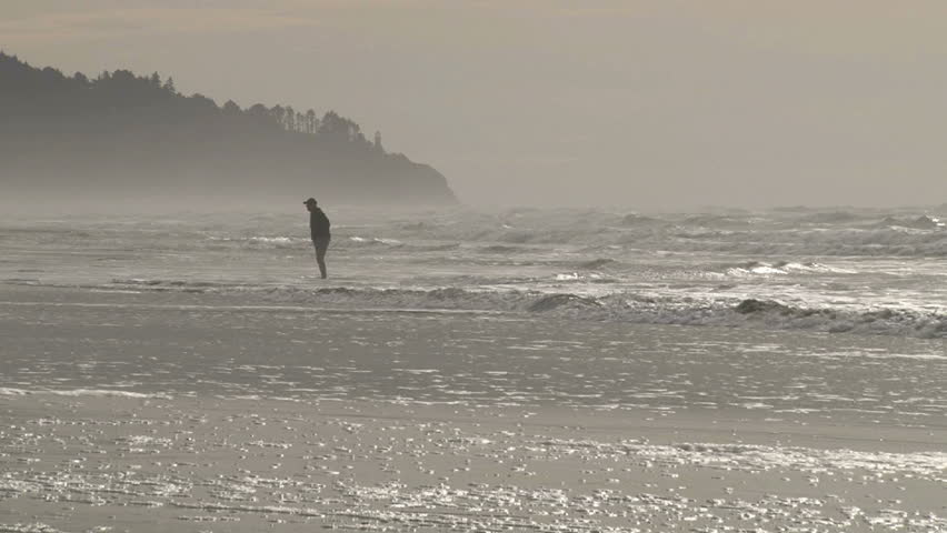Man stands in Pacific ocean as tide comes in and two friends join.