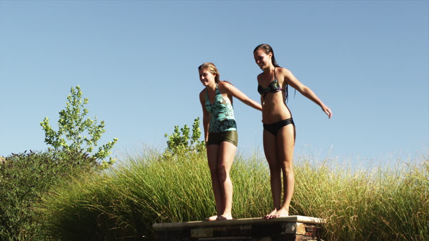 SLO MO Wide Shot Two teenage (16-17) girls jumping into swimming pool