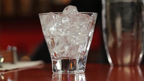 Bartender pours a cocktail in a glass (close-up)