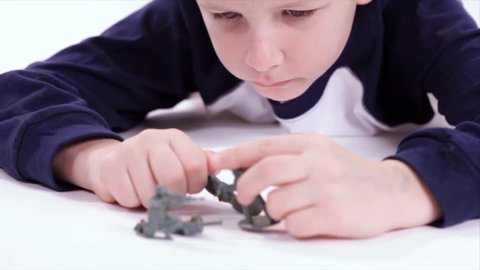 A young boy plays with old fashion toy soldiers. Taken on a white backdrop. Rack Focus
