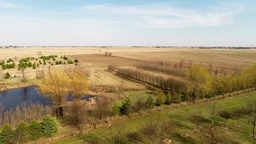 Aerial view flyover Illinois farmland in early spring with creek open fields and country house