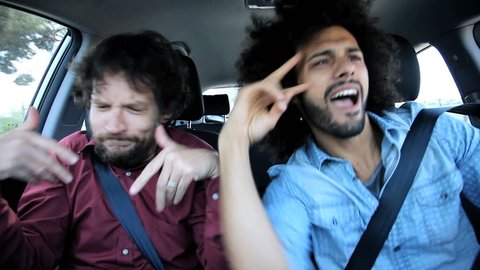 Two drunk friends in car celebrating after party singing and dancing driving car