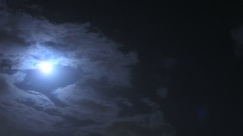 Time lapse of the Blue light of the moon shining through speeding clouds