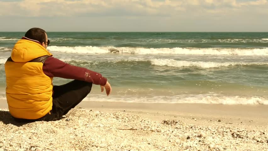 a man sitting on the beach and watching the waves