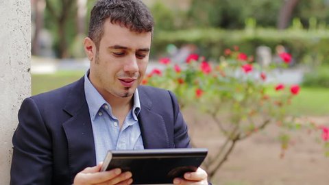 Young businessman with tablet computer in park