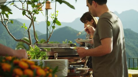 Medium Shot Couple serving food onto plates at self serve outdoor restaurant / Ravello, Campania, Italy